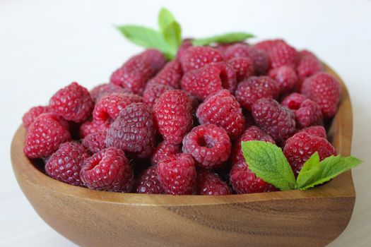 Close-up of a raspberry in a wooden container on a white background