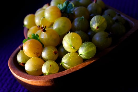 Harvest of gooseberries on a wooden plate.Texture or background