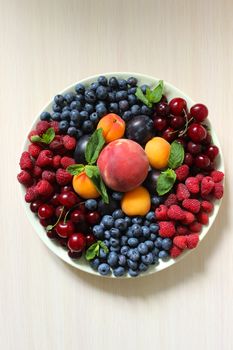 Mix of berries on the table on a white plate .Texture or background