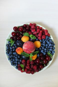 Berry mix on a white plate on a white background.Texture or background