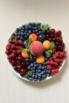 Mix of berries on the table on a white plate .Texture or background