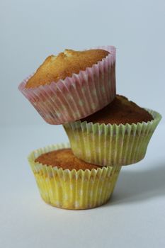 Three cupcakes in a yellow wrapper on a light background .Texture or background