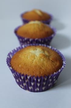 Three cupcakes in a blue wrapper on a light background .Texture or background