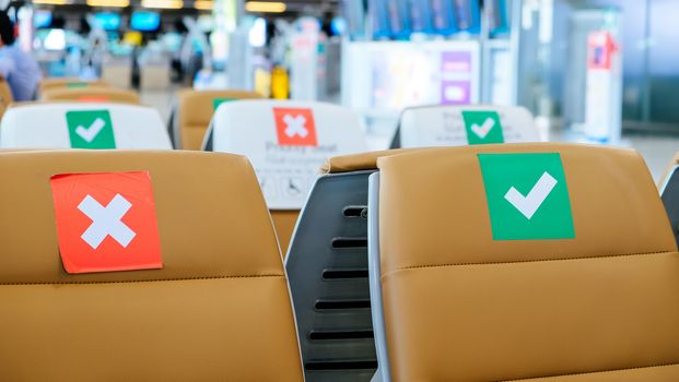 Social distancing, Rows of empty chairs in an airport's departure area marked with symbols regarding social distancing protocol to prevent the spreading of novel corona virus, COVID-19 in Thailand