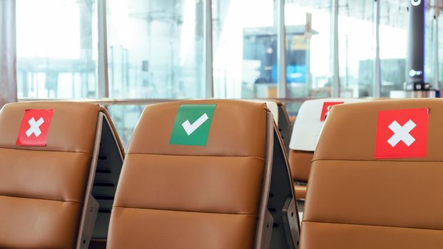 Social distancing, Rows of empty chairs in an airport's departure area marked with symbols regarding social distancing protocol to prevent the spreading of novel corona virus, COVID-19 in Thailand