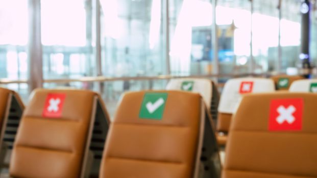 Social distancing, Blurred image of empty chairs in an airport's departure area marked with symbols regarding social distancing protocol to prevent the spreading of novel corona virus, COVID-19