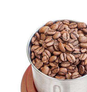 A lot of coffee beans in a metal coffee grinder on a white background. The view from the top. Isolated