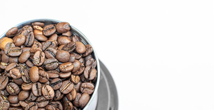 A lot of coffee beans in a metal coffee grinder on a white background. The view from the top. Isolated