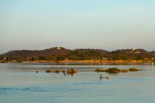 Muong Khong Laos 1/12/2012 Mekong river at sunset in blue hour and traditional fishing boats with nets golden Buddha in the distance . High quality photo