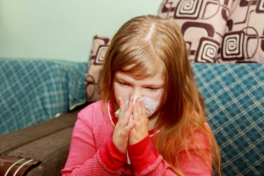 Little girl has a runny nose and blows her nose into a paper handkerchief on background