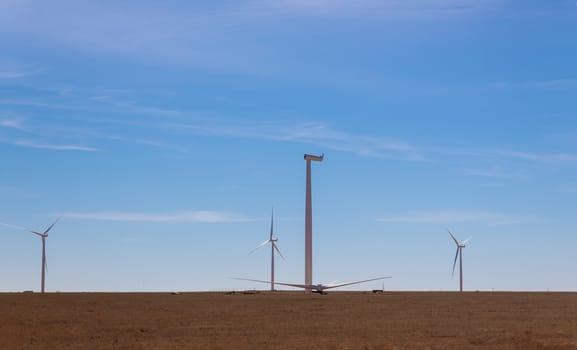 A panoramic view of the windmill in a field installation wind turbine with blue sky background