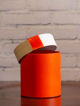 Orange color cylindrical gift box with white lid with orange ribbon, Christmas gift package
