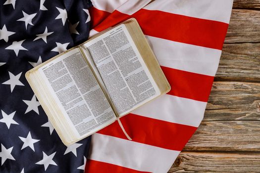 Los Angeles CA US 16 MAY 2020: Open is reading Holy Bible book with prayer for america over ruffle American flag on wooden table
