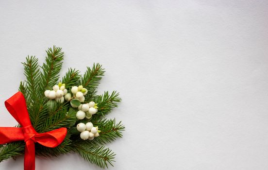 Christmas bouquet with fir branches, red bow and white dogwood berries on a white background . Christmas card. The theme of a winter holiday. Happy New Year.