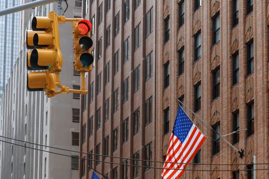 American flag in front of business building with traffic light shining red New York US