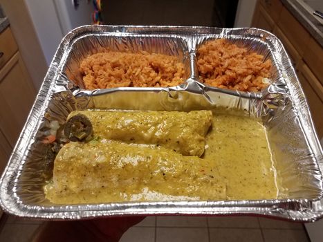 hand holding container of spicy enchiladas and rice Mexican food