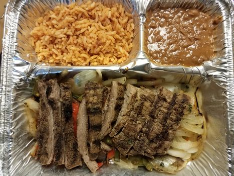 steak fajita meat with rice and beans in metal container or tray