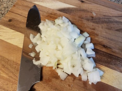 sharp knife on wood cutting board with white onions