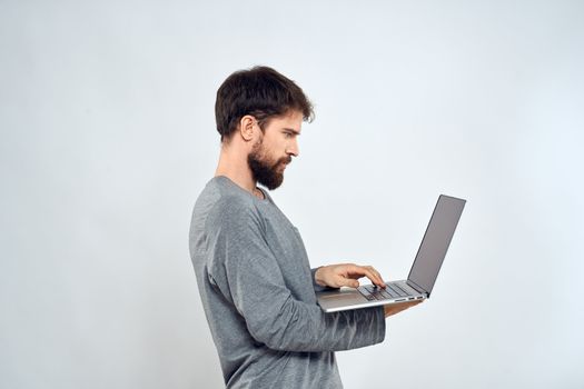 Bearded man with laptop in hands internet communication technology light background. High quality photo