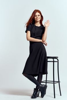 woman high chair indoors full length black dress red hair model boots. High quality photo