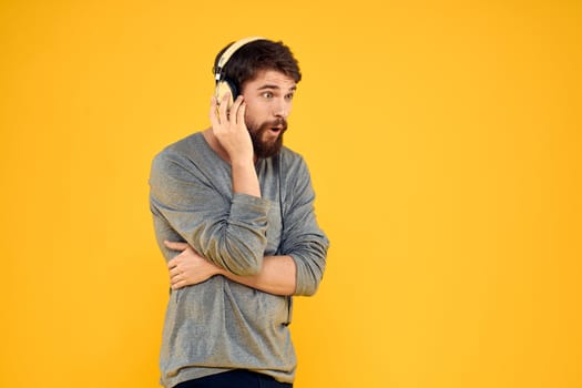 Man in headphones listens to music technology lifestyle fun people yellow background. High quality photo