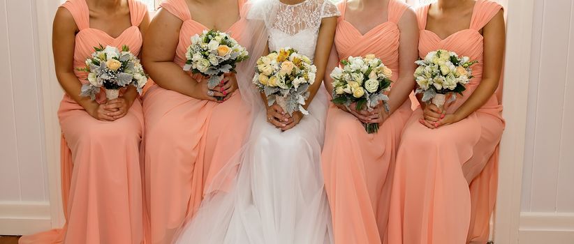 A bride with her bridesmaids all holding their bouquets and posing prior to the wedding ceremony