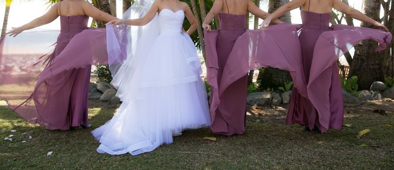 A bride with her bridesmaids having fun in a garden prior to her wedding