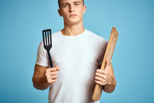 energetic guy with wooden kitchen board and spatula fun emotions. High quality photo