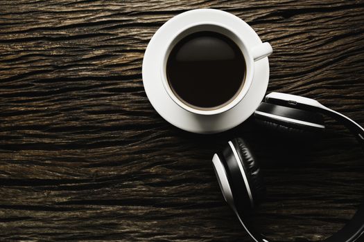 A cup of coffee with headphone on wooden table. Top view of coffee with copy space. Drink concept.