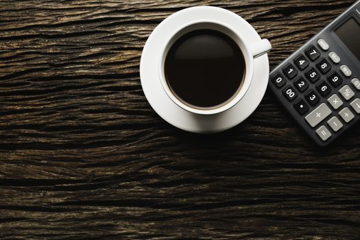 Wooden table wooden desk with coffee and calculator. Top view of Coffee cup on wooden background with copy space.