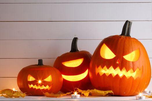 Halloween pumpkin head lanterns and burning candles on wooden background