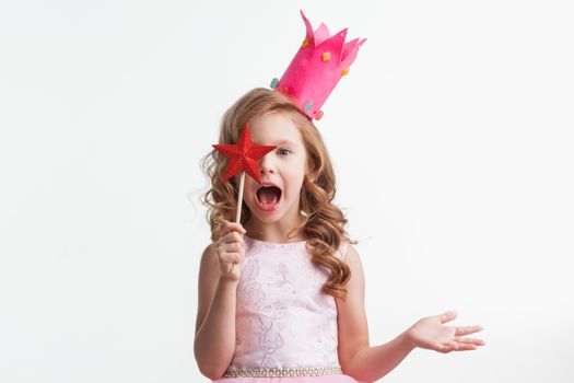 Beautiful little candy princess girl in crown holding star shaped magic wand putting spell isolated on white