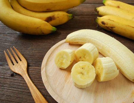Bananas and banana slices on a plate of wood.