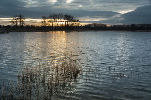 Sunset and dark clouds over the calm lake