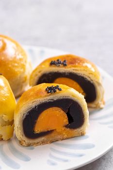 Tasty baked egg yolk pastry moon cake for Mid-Autumn Festival on bright cement table background. Chinese traditional food concept, close up, copy space.