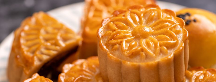 Tasty baked egg yolk pastry moon cake for Mid-Autumn Festival on bright cement table background. Chinese traditional food concept, close up, copy space.