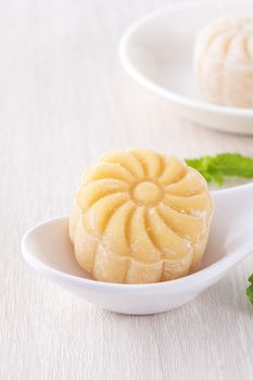 Colorful snow skin moon cake, sweet snowy mooncake, traditional savory dessert for Mid-Autumn Festival on bright wooden background, close up, lifestyle.