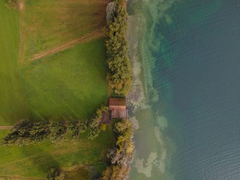 drone shot. Birds view of clear lake with trees and buildings