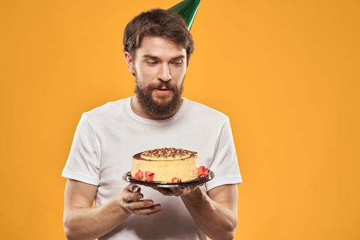 A bearded man with a cake and in a cap celebrating his birthday. High quality photo