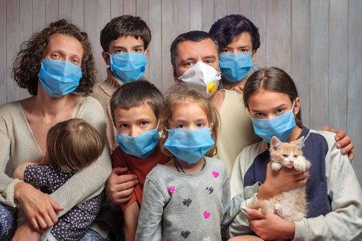 Large traditional family in blue face masks. Portrait of a family having six children in protective medical masks on a wooden wall background. Looking at camera. Stay home during COVID-19 coronavirus