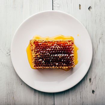 Top view of delicious yummy honeycomb on bright plate over light wooden background