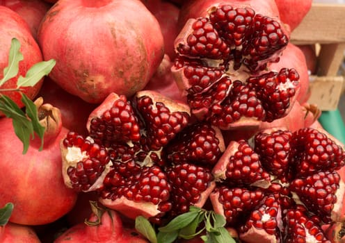 Ripe red pomegranates on the market. Cut pomegranates, herbs