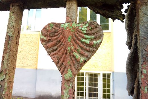 Old rusty peeling heart - an element of an old fence.