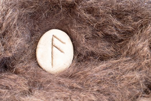 Ansuz Nordic stone rune on fur. Letter Aesc of the Viking alphabet.