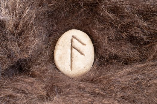 Ansuz Nordic stone rune on fur. Letter Aesc of the Viking alphabet.