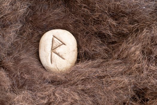 Raido or Raidho Nordic stone rune on fur. Letter Raed of the Viking alphabet.