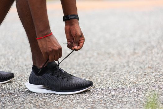 Close up Asian sport runner black man standing he trying shoelace running shoes getting ready for jogging and run at the outdoor street health park, healthy exercise workout concept