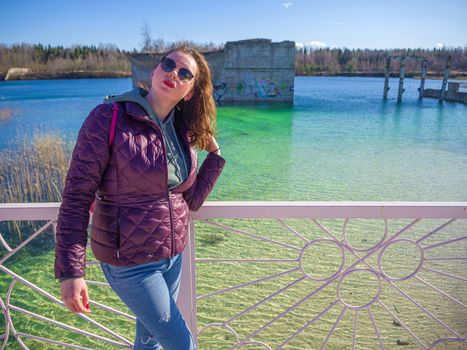 Hiker on mountain top. Woman is standing with an Abandoned Quarry and water on the background. Scenic View Of Land Against Clear Blue Sky. Panoramic View.