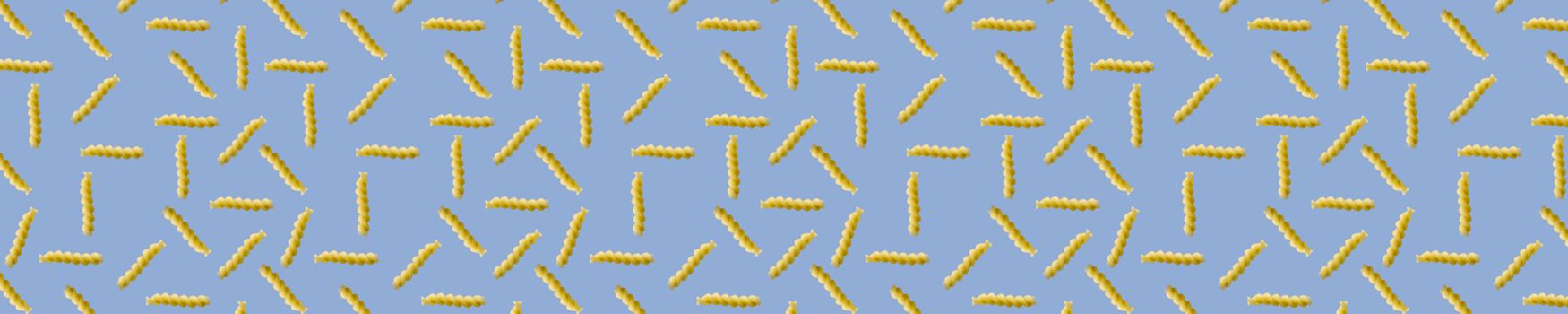 Fusilli pasta random flat lay on blue background without shadow. can be used as raw pasta background, poster, banner not pattern