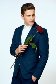 A man in a suit with a rose in his hands a gift date light background. High quality photo